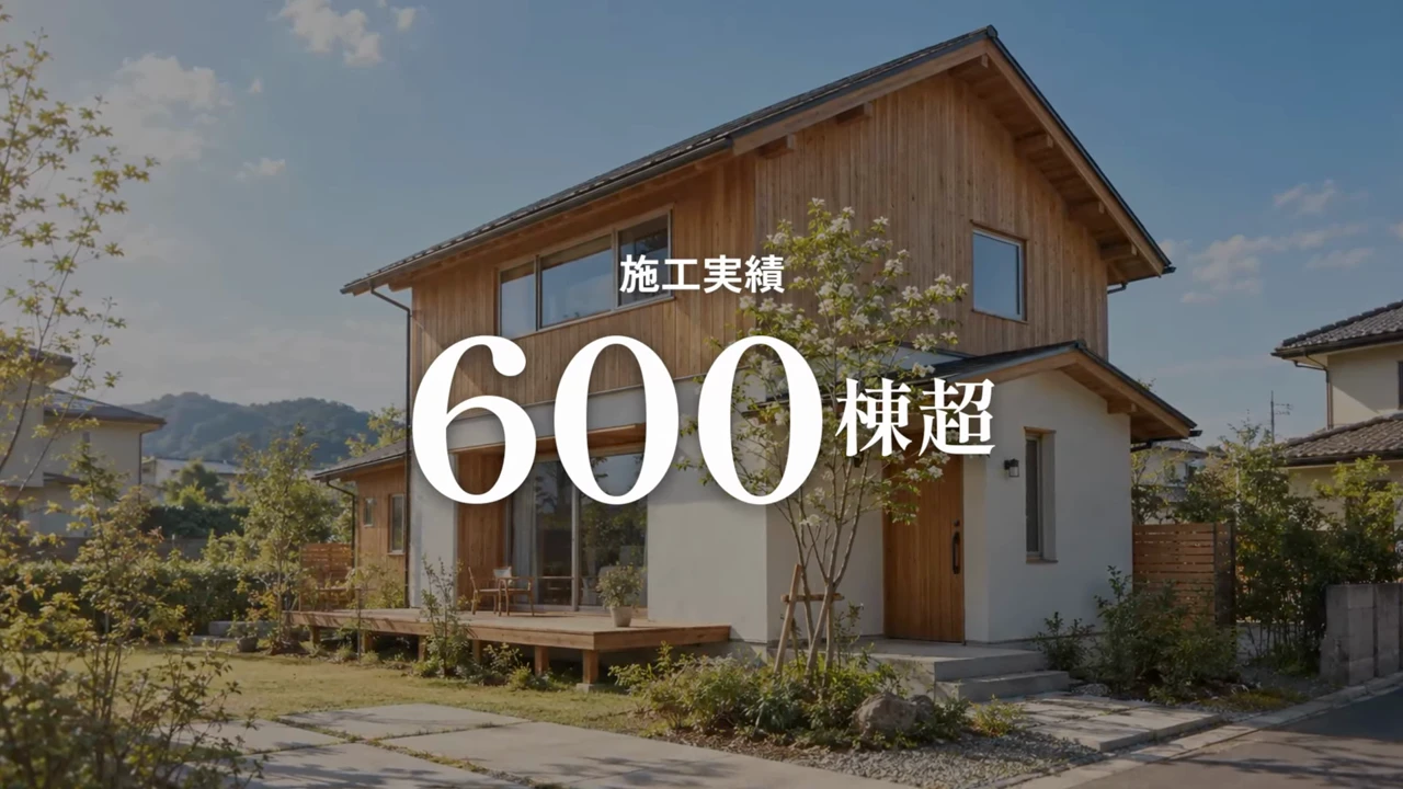 作例の会社紹介動画の場面。木の外壁の2階建ての家に「施工実績 600棟超」の大きな文字が重なっている