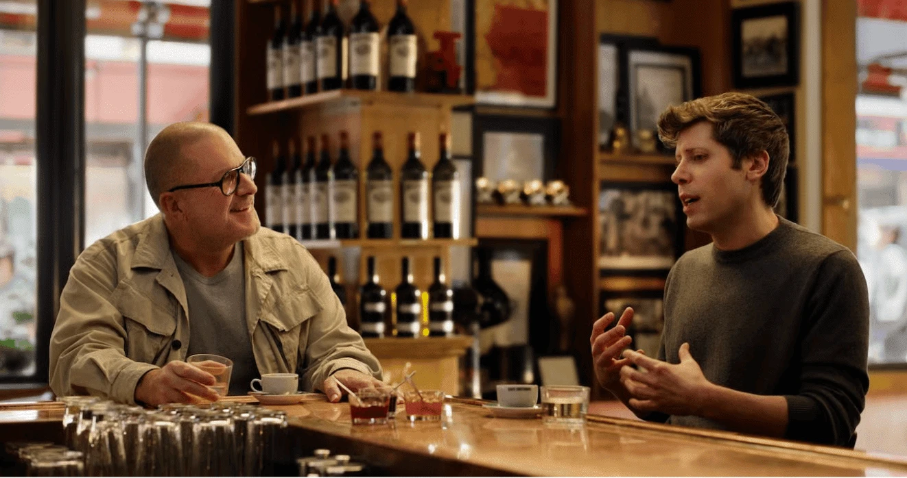 Former Apple designer Jony Ive and OpenAI CEO Sam Altman talking across a bar counter